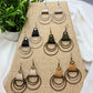 Collection of earrings on a display stand with a plant in the background