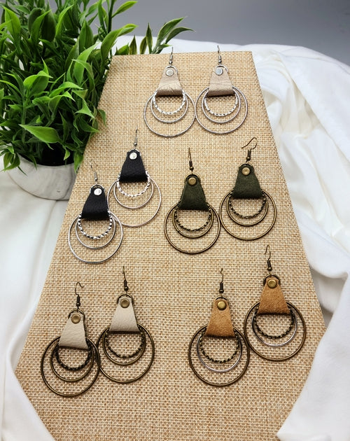 Collection of earrings on a display stand with a plant in the background
