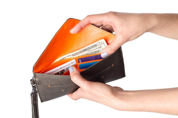 Person holding an open wallet with money and cards on a white background