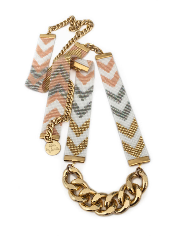 Necklace with gold chain and chevron-patterned arm bands on a white background