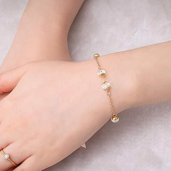 Gold bracelet with small beads on a wrist against a neutral background