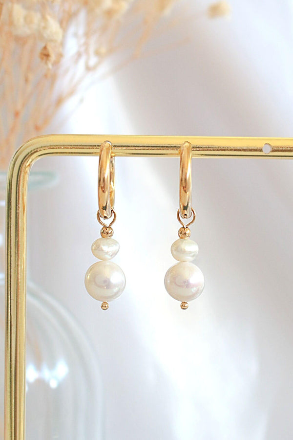 Pearl earrings on a gold stand with a soft background