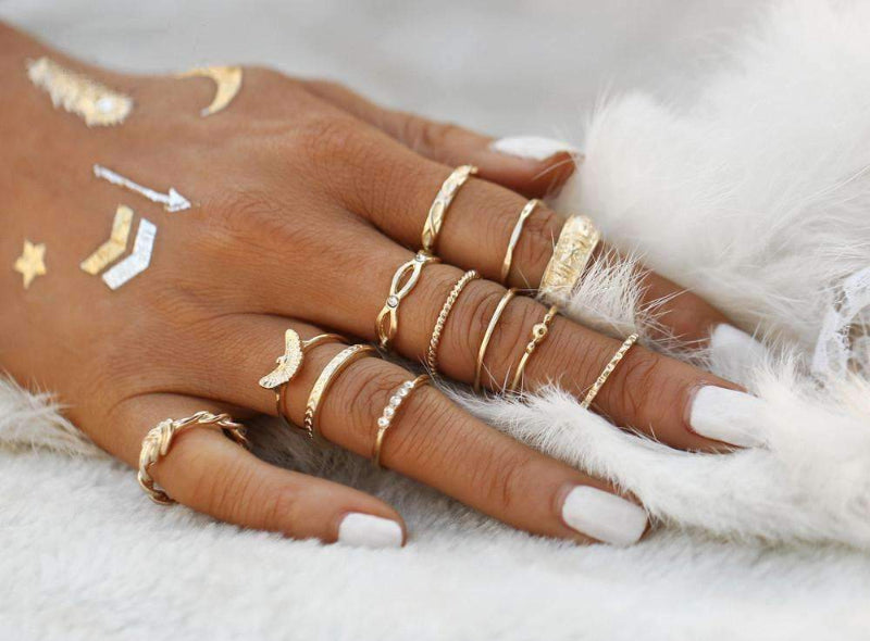 Hand wearing multiple gold rings on a soft white background