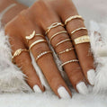 Close-up of a hand wearing multiple gold rings on a white fur background