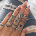 Hand wearing multiple silver rings with gemstones against a denim background