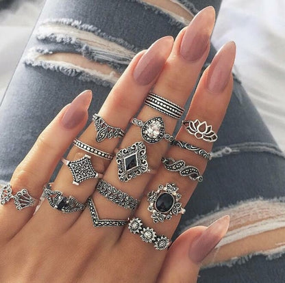 Hand wearing multiple silver rings with gemstones against a denim background