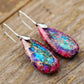 Colorful teardrop earrings on a wooden surface