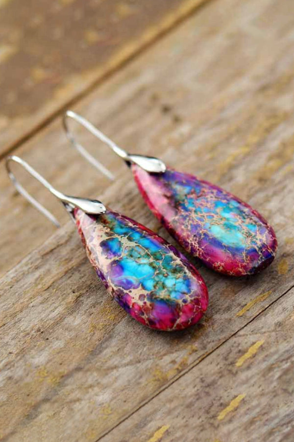 Colorful teardrop earrings on a wooden surface