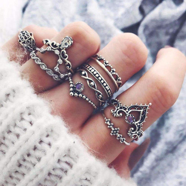 Close-up of a hand wearing multiple decorative rings with intricate designs.