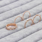 Set of rose gold rings with gemstones on a textured surface
