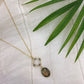 Necklace with a pendant on a white fabric background with green leaves