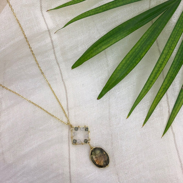 Necklace with a pendant on a white fabric background with green leaves
