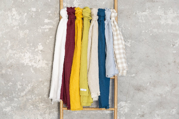 Colorful scarves on a wooden rack against a textured gray wall