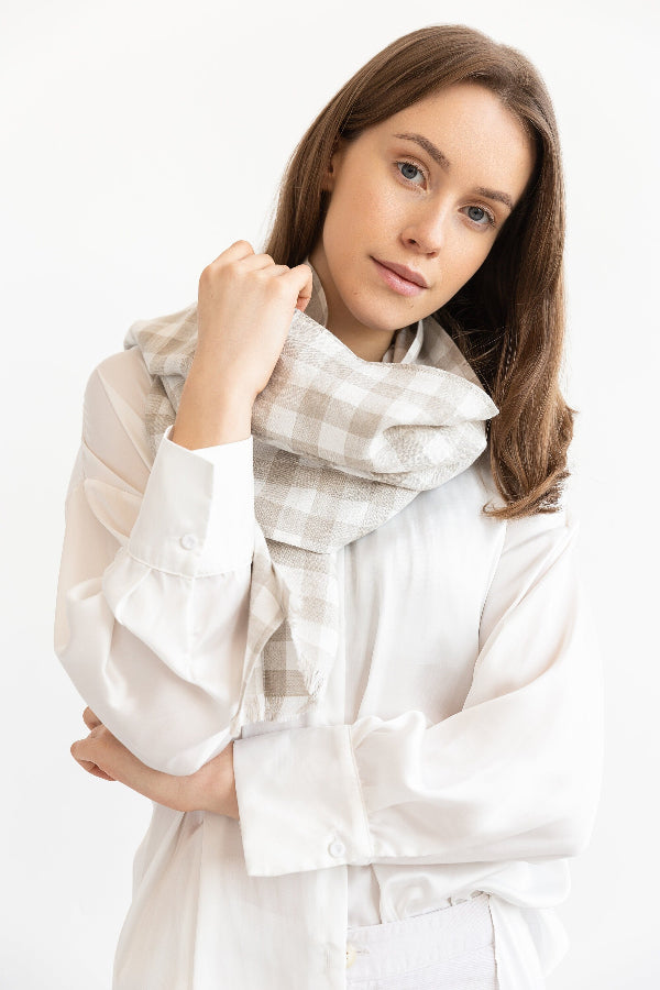Woman wearing a white outfit with a checkered scarf on a white background