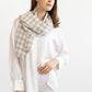 Woman wearing a light-colored scarf with a checkered pattern on a white background