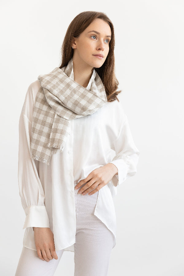 Woman wearing a light-colored scarf with a checkered pattern on a white background