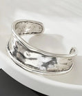 Silver cuff bracelet on a white surface