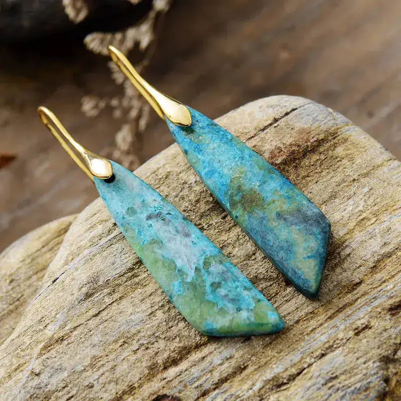 Teal earrings with gold hooks on a stone surface