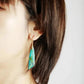 Close-up of a turquoise earring worn by a person with brown hair.