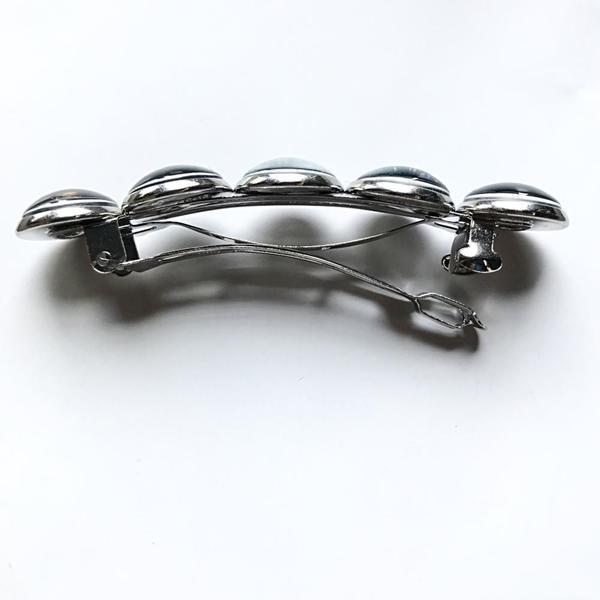 Silver brooch with five round elements on a white background