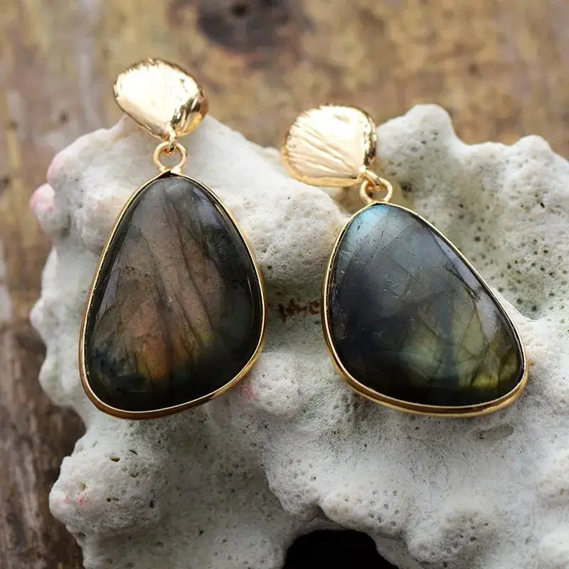 Gold-framed labradorite earrings on a textured stone surface