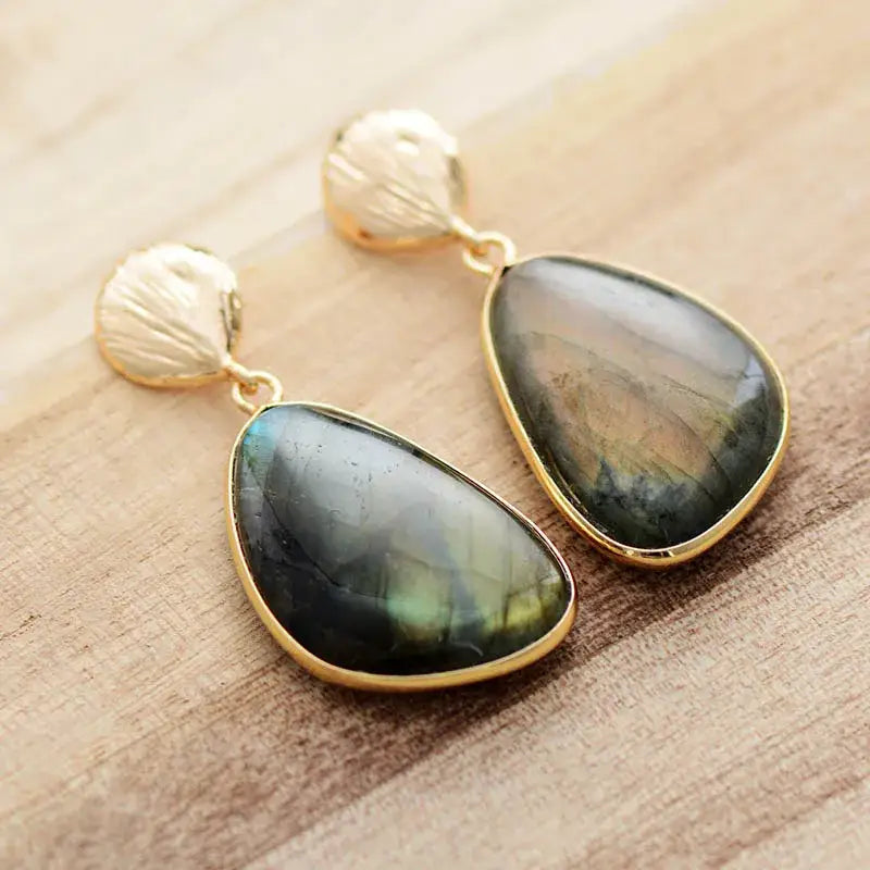 Gold earrings with green gemstones on a wooden surface