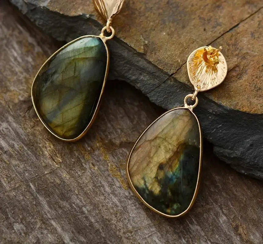 Gold-framed labradorite pendant on a stone surface
