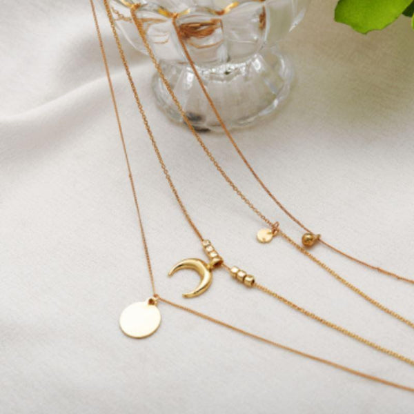 Gold necklaces with various pendants on a white surface