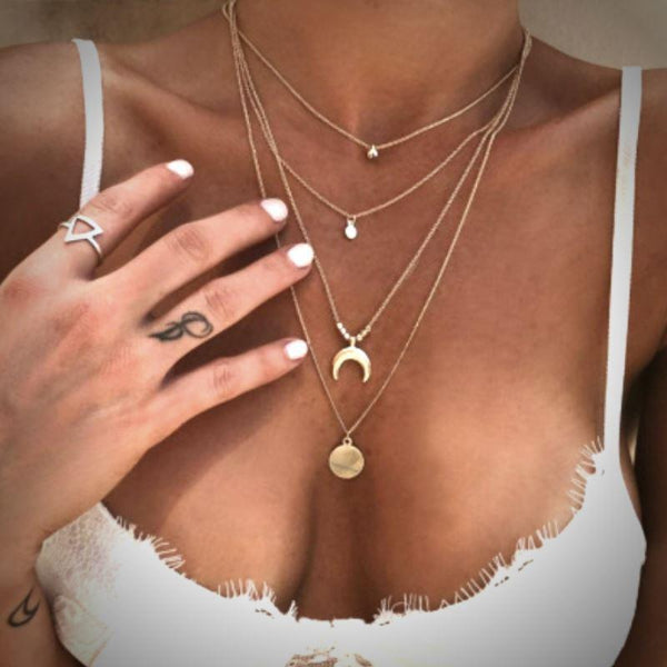 Layered gold necklaces on a person wearing a white top.