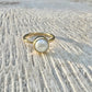 Gold ring with a pearl on a textured stone surface