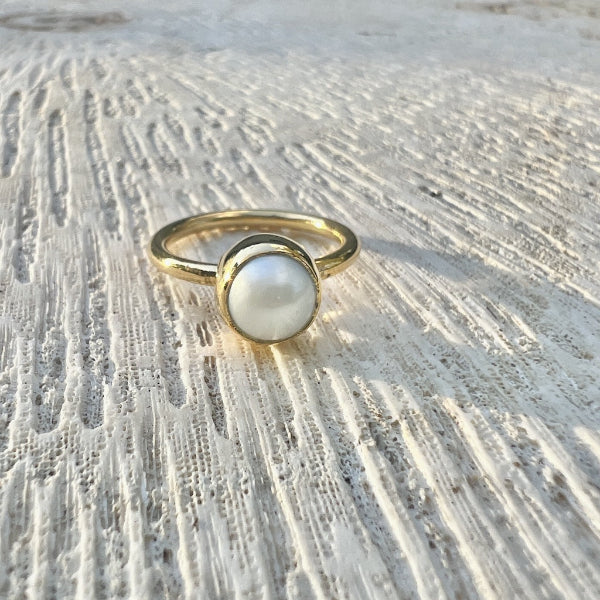 Gold ring with a pearl on a textured stone surface