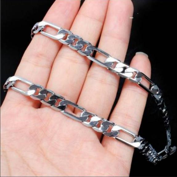 Silver chain bracelet on a hand against a black background