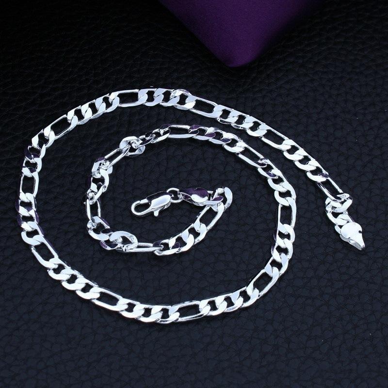 Silver chain necklace on a textured black surface