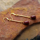 Gold earrings with red stones on a textured surface