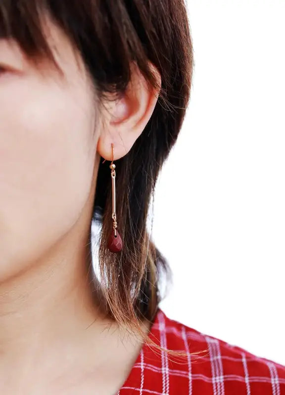 Close-up of a person wearing a red earring with a white background