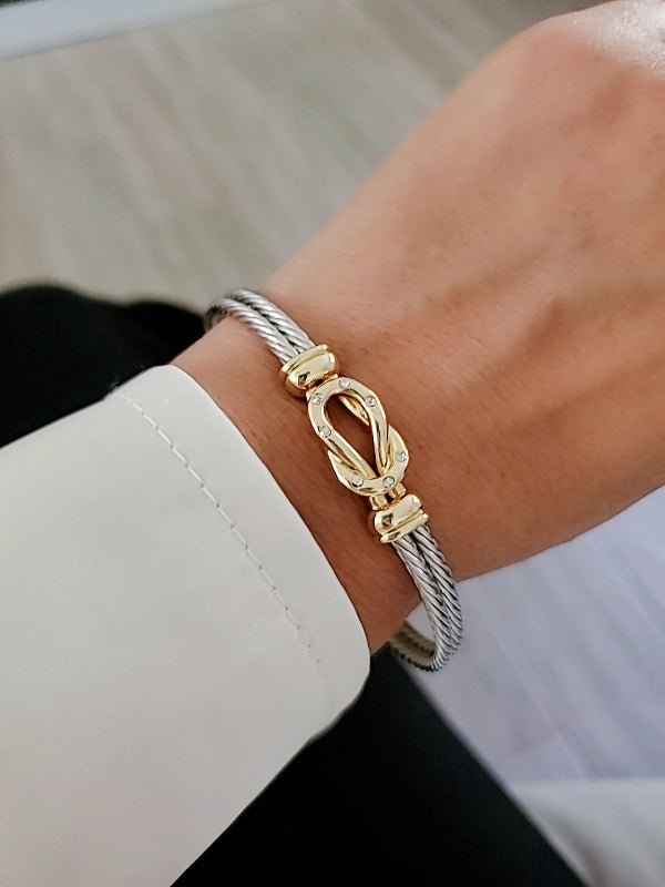 Gold and silver bracelet on a wrist with a blurred background