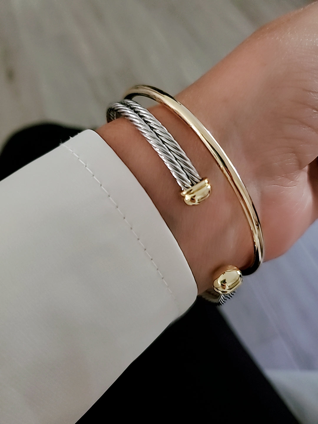 Gold and silver bracelets on a wrist with a blurred background