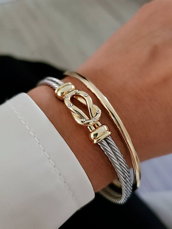 Gold and silver bracelet on a wrist with a blurred background