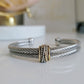 Silver bracelet with a gold accent on a white surface