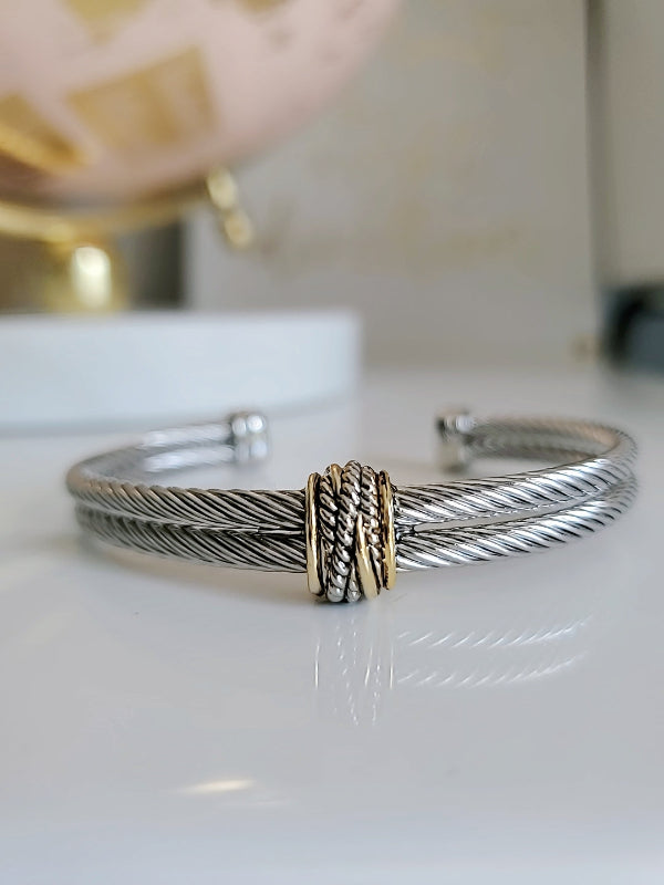 Silver bracelet with a gold accent on a white surface