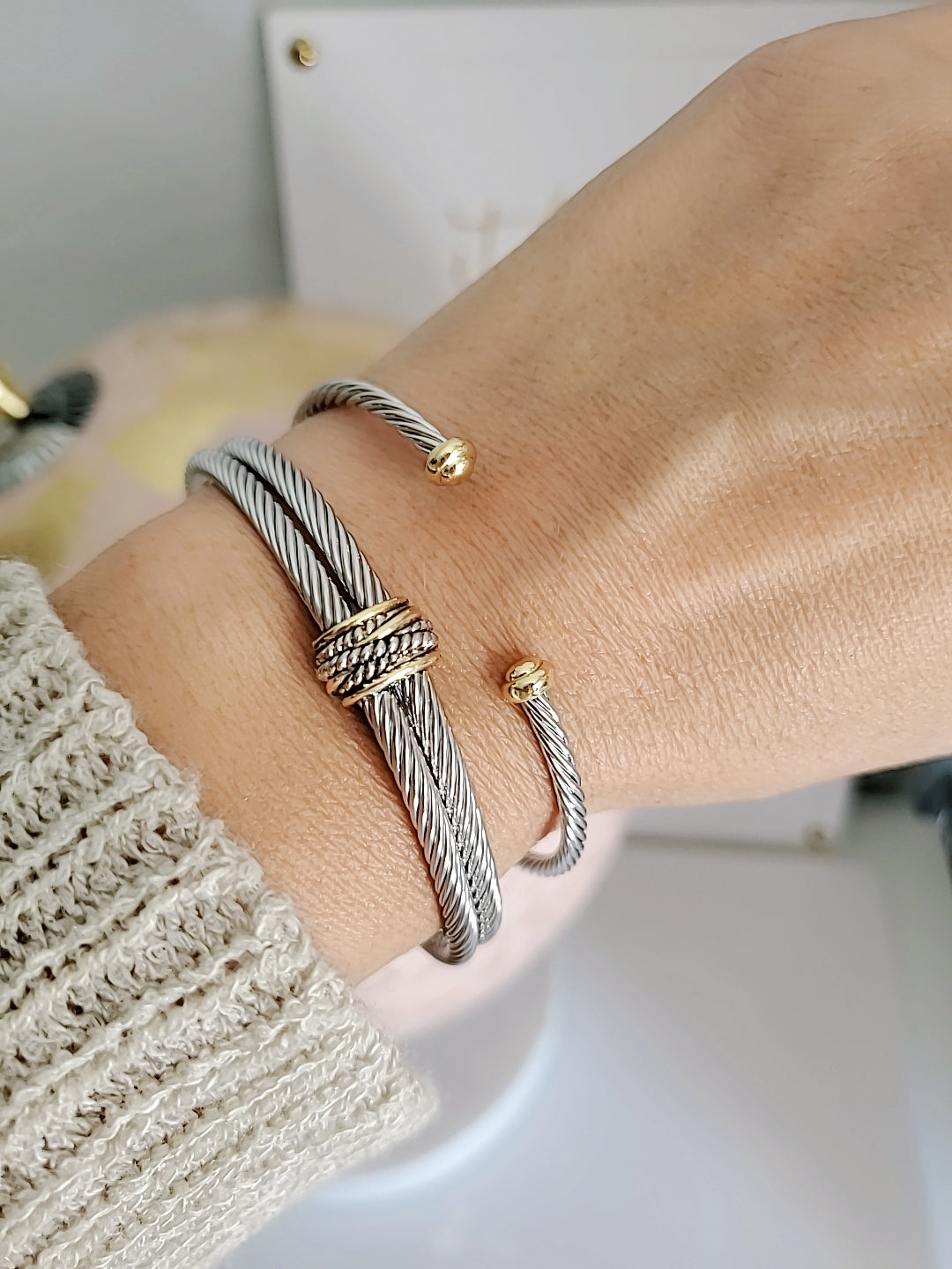 Close-up of a wrist wearing multiple bracelets on a neutral background