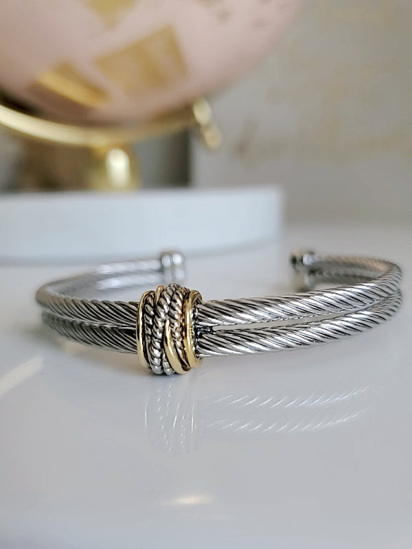 Silver bracelet with a gold accent on a white surface