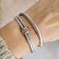 Silver bracelet with gold accents on a wrist against a neutral background