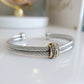 Silver bracelet with gold accent on a white surface