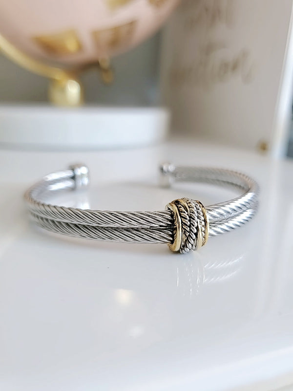 Silver bracelet with gold accent on a white surface