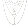 Stack of silver necklaces with geometric pendants on a white background