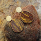 Gold and stone earrings on a textured rock surface