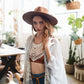Woman wearing a hat and casual outfit in a home setting with plants and furniture.