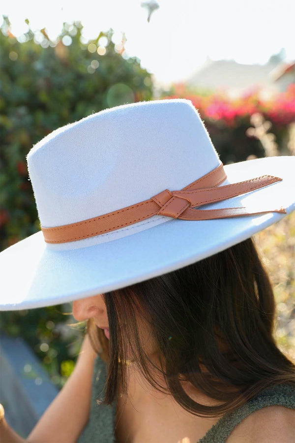 White hat with a brown band worn by a person outdoors